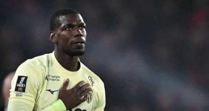 ফ্রান্সের মিডফিল্ডার পল পগবা হালকা হলুদ জার্সি পরে মাঠে দাঁড়িয়ে আছেন, হাত বুকে রাখা এবং চোখে আবেগের ছাপ।